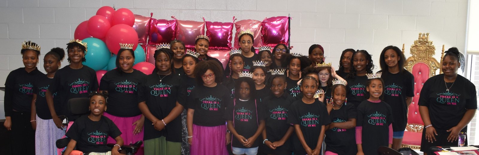 A group of girls gathered in crowns and matching There Is a Queen in Me shirts at an Enough Period event