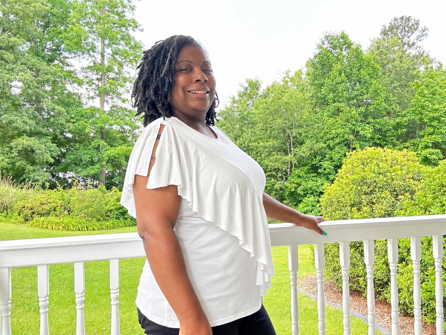 TiffMichelle standing on a porch in a white shirt